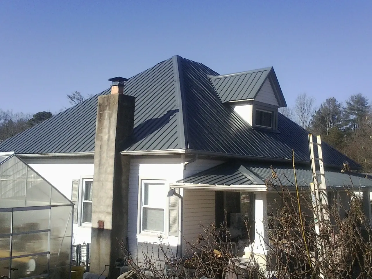 Dark blue standing seam metal roof on a white farmhouse with dormer — Slate & Tile Roof Repair by Roofing Brothers in Sagamore