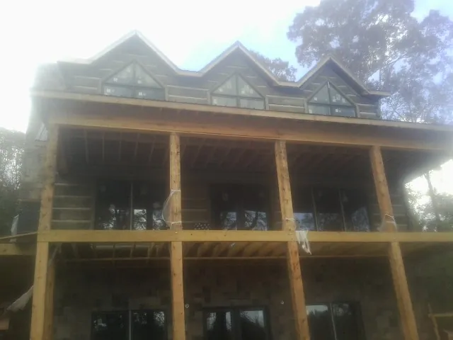 Dormers and porch framing on a large log home under construction — Roof Coating work by our crew in Sagamore