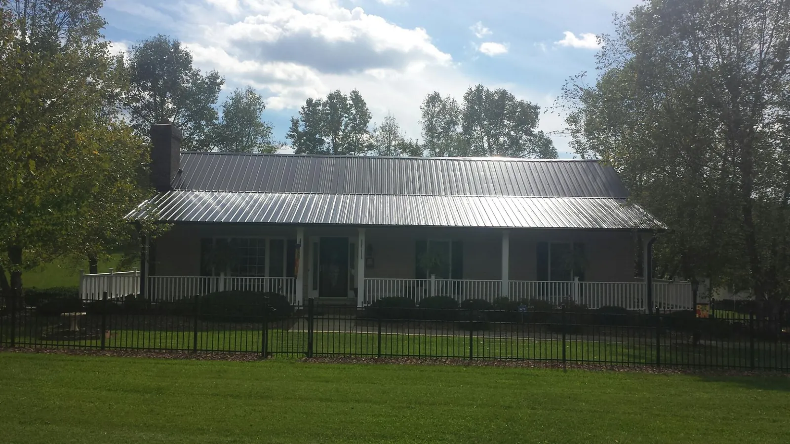 Gray metal roof on a brick ranch with a full width front porch — Gutter Guard Installation work by our crew in Sagamore