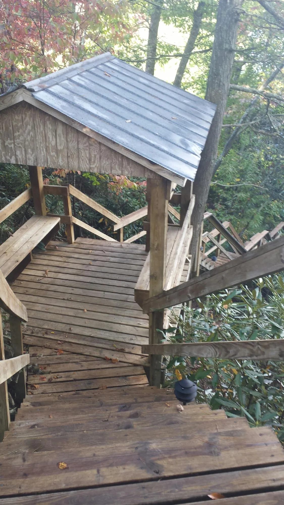 Metal roofed shelter over wooden steps on a wooded walkway — Skylight Repair & Installation work by our crew in Sagamore