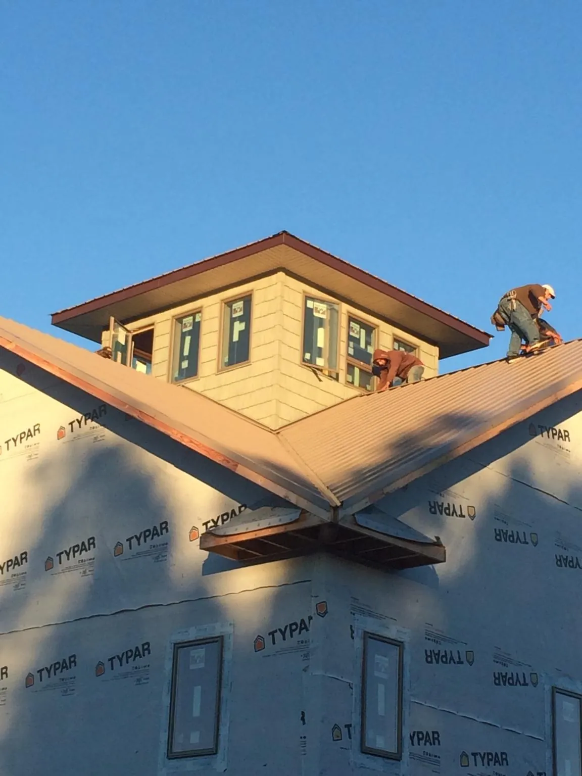 Roofers working around a rooftop cupola on a new metal roof at sunset — Roof Waterproofing in Sagamore by Roofing Brothers